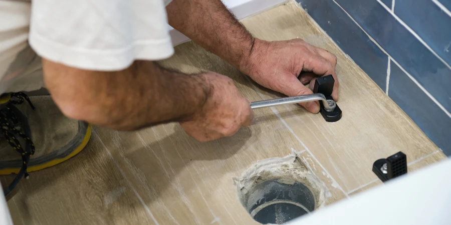 Unrecognizable senior plumber installer installing toilet drain flange in a house