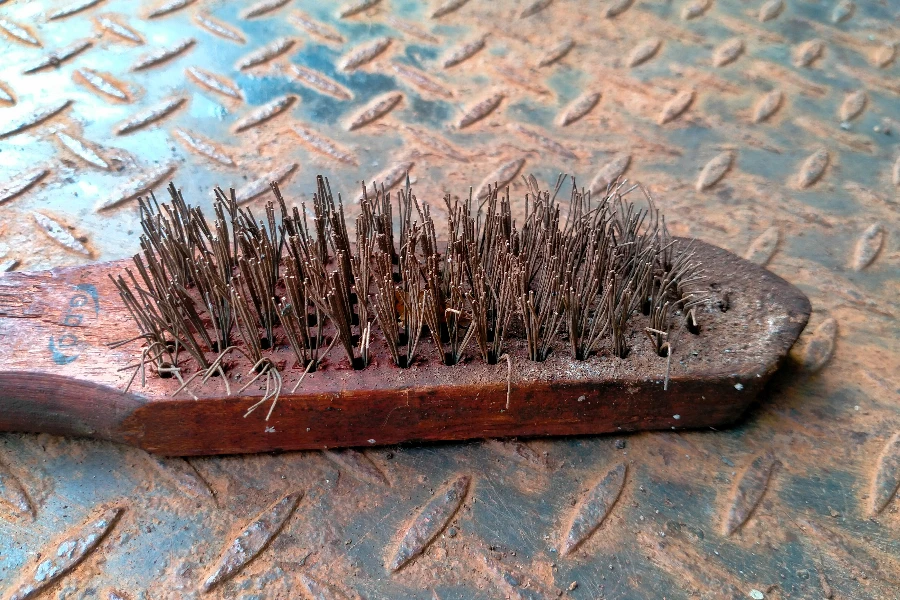 Old used Steel wire brush tool on a corroded iron textured background
