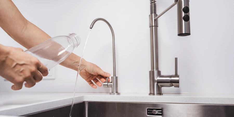 Woman get filtered water from stainless faucet into reusable bottle