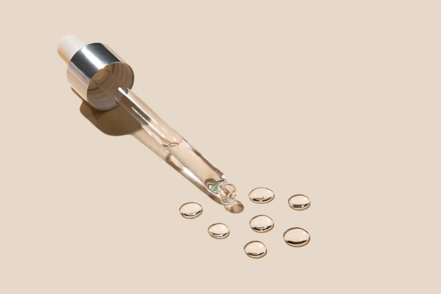 Cosmetic pipette with drops of gel on a beige background