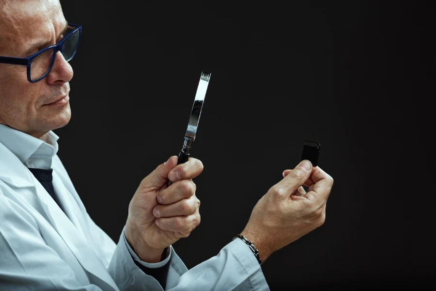 A lab technician observes a memory card with a magnifying lens