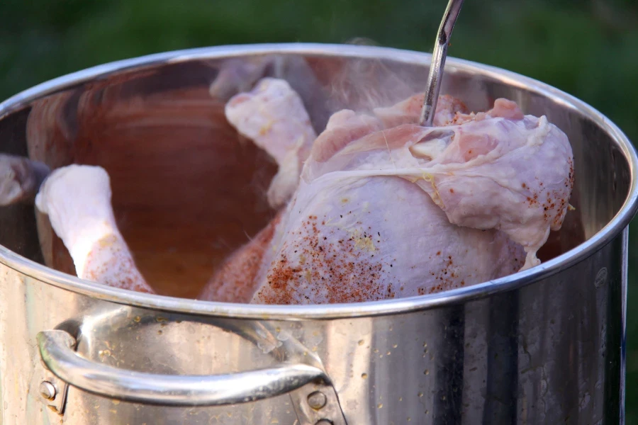 Turkey with spices on it being placed into a deep fryer
