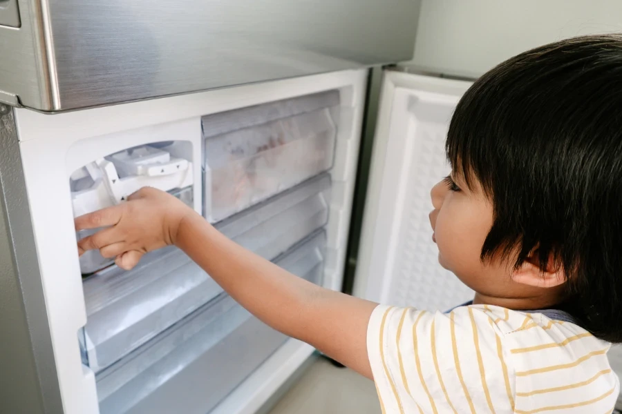 Little boy trying to get some ice from the ice maker
