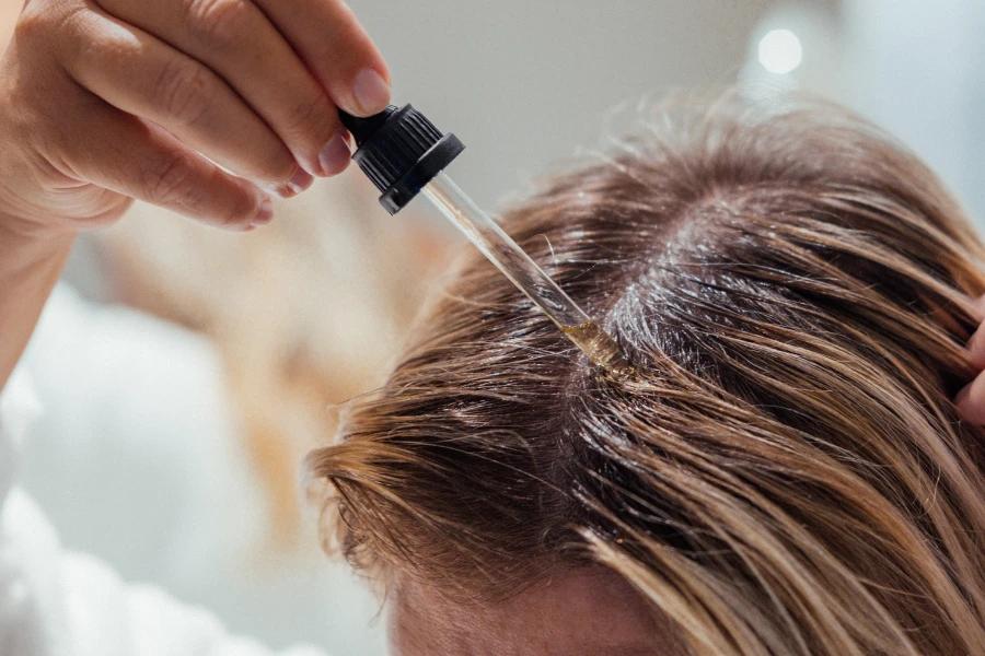 Woman applies oil to her hair with pipette

