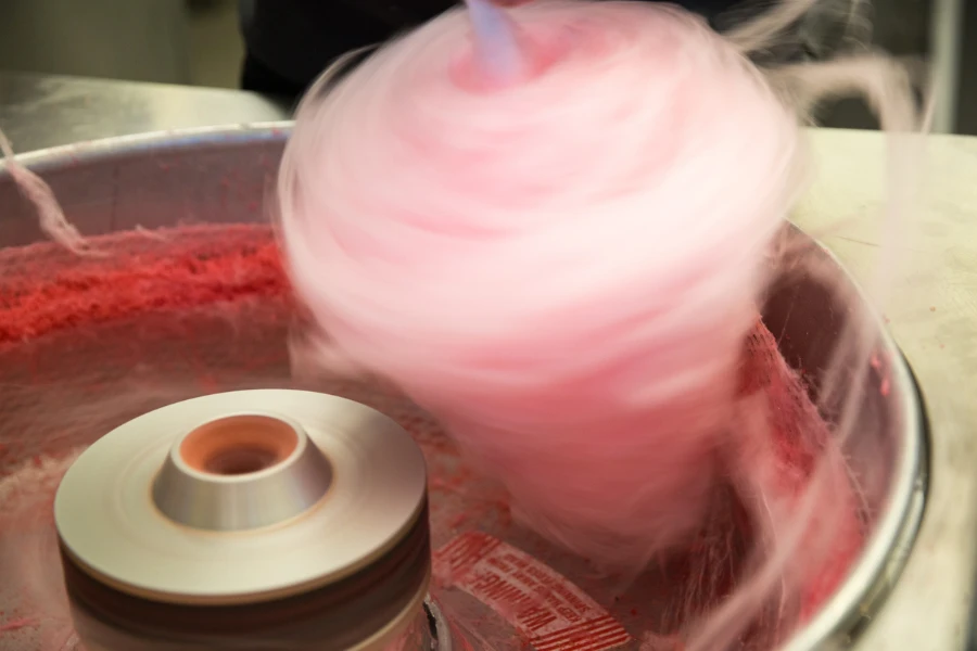 Pink cotton candy spinning fast as it is being made in a machine
