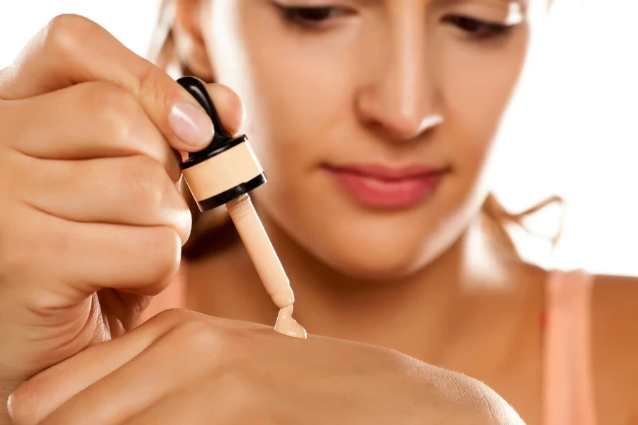 young woman puts a liquid foundation on her palm
