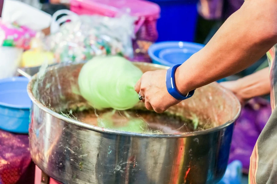 Hand rolling cotton candy in candy floss machine
