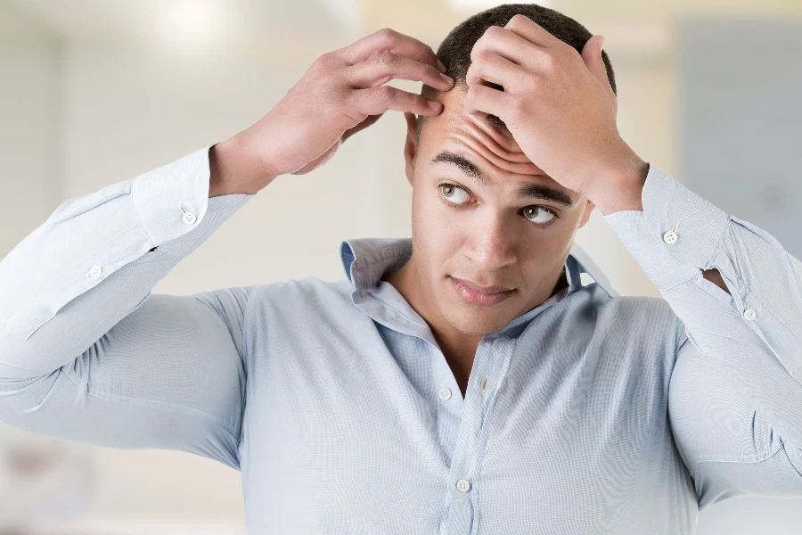 Man checking hairline, in a bathroom
