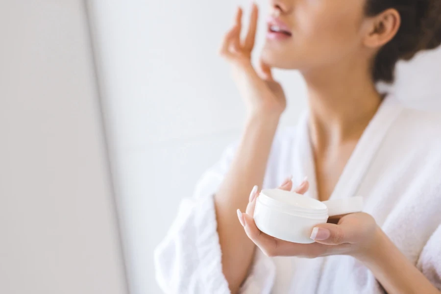 Woman caring of her beautiful skin face standing near mirror in the bathroom