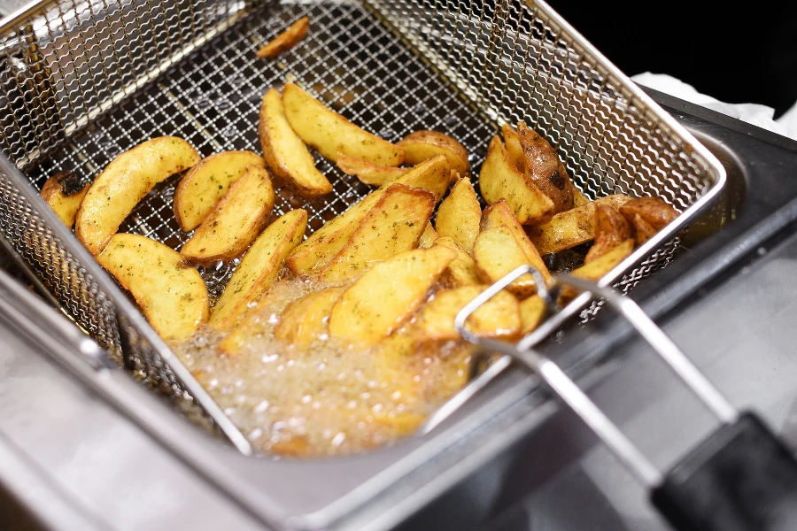 Spicy potato chips or wedges cooking in a deep fryer
