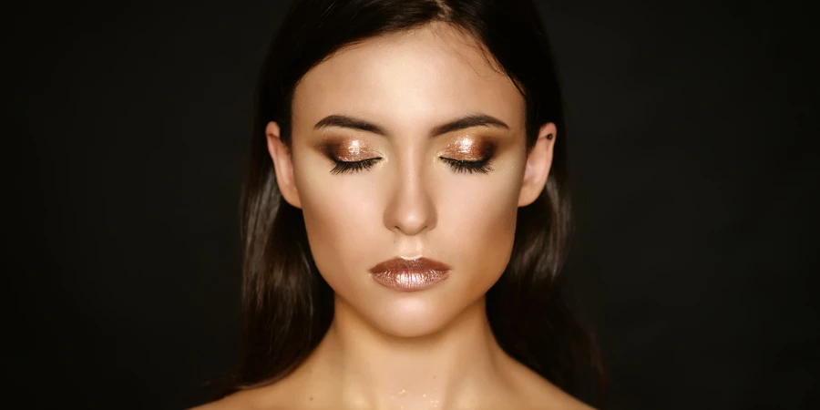 Close-up portrait of young woman with golden makeup
