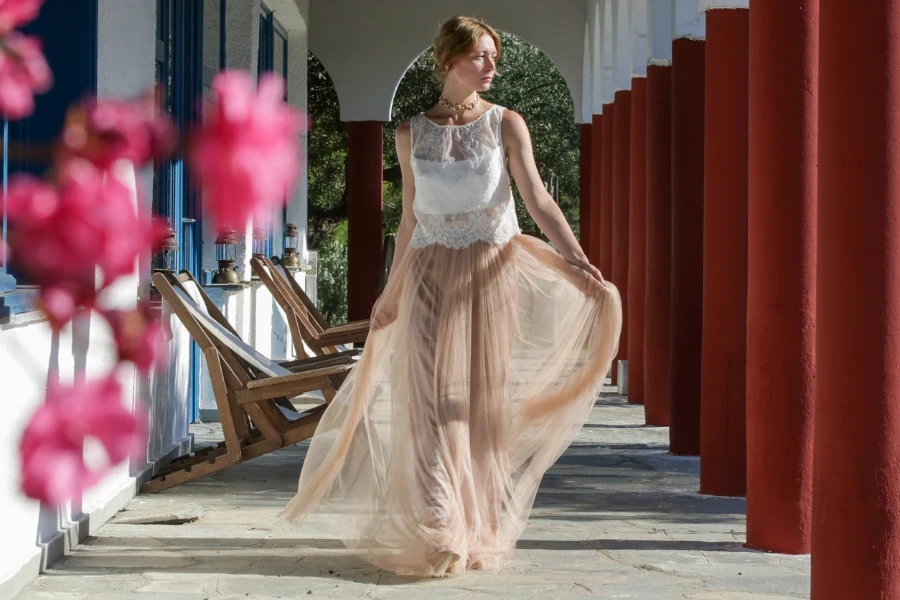 Fashion portrait of woman in white lace top and chiffon long maxi beige skirt