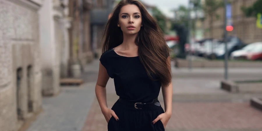 Fashion style portrait of young beautiful elegant woman in black dress walking at city streets