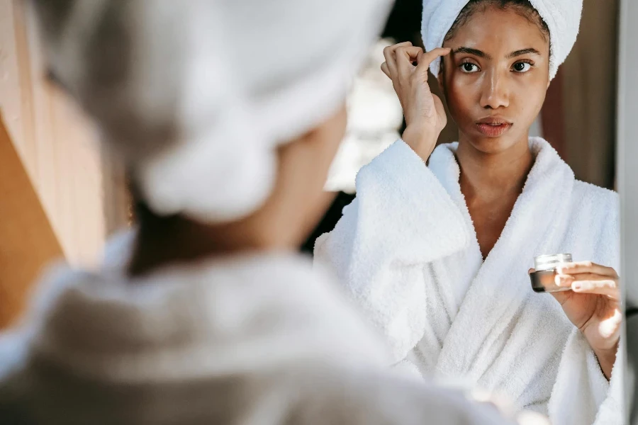 Woman rubbing cream on face after bath