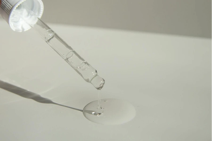 Anonymous person pouring liquid product on table with pipette 