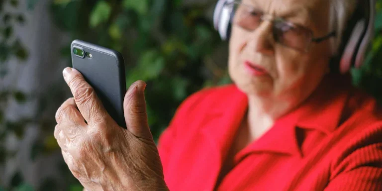 A Man in Red Shirt Using a Phone while Wearing Headphones