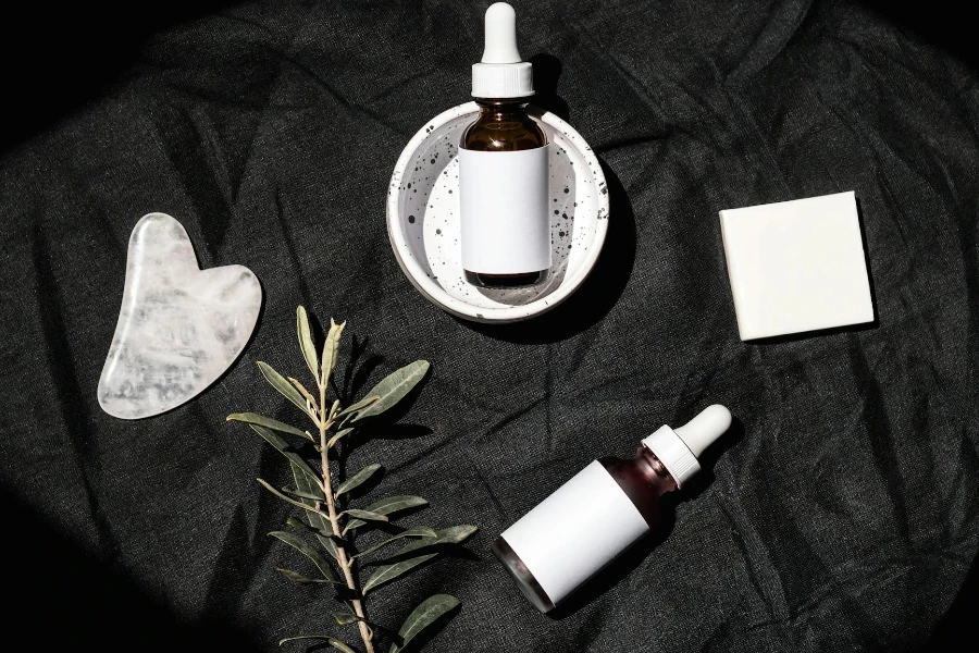 Brown Glass Bottles on Black Textile Beside Gua Sha and Leaves