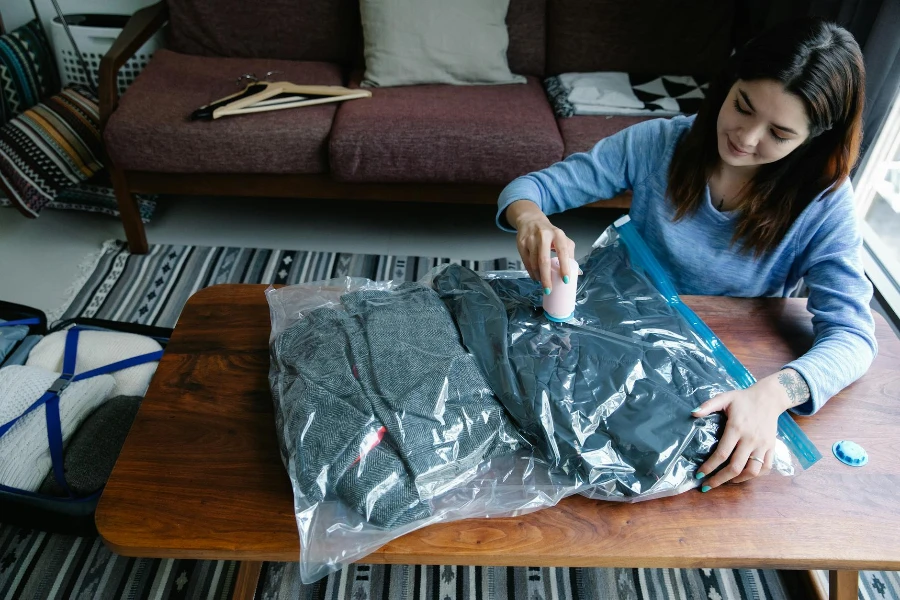 A Woman Vacuum Packing Clothes on a Table