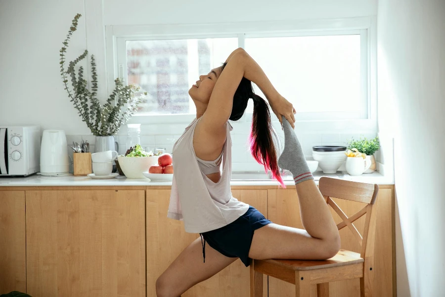 Asian woman stretching leg on wooden chair