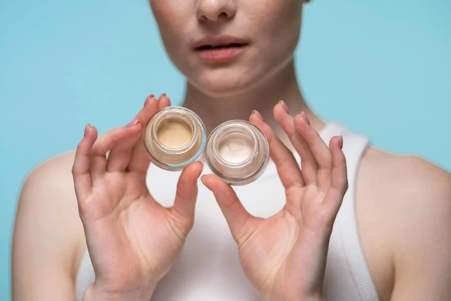 Foto recortada de una mujer sosteniendo productos cosméticos