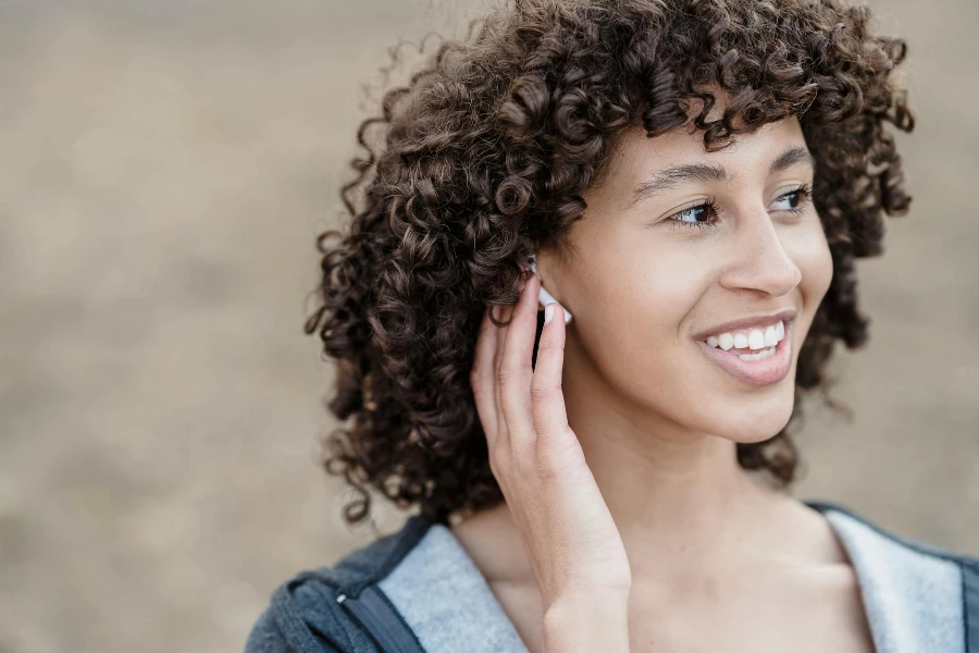 female looking away with smile while listening to songs in wireless earphones