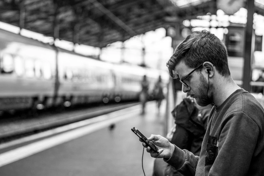 Photography of Man Holding Phone at Train Station