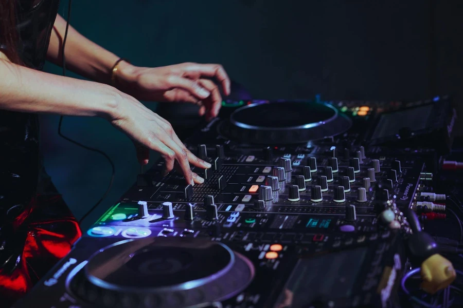 Woman DJ Touching Faders of a Mixing Board