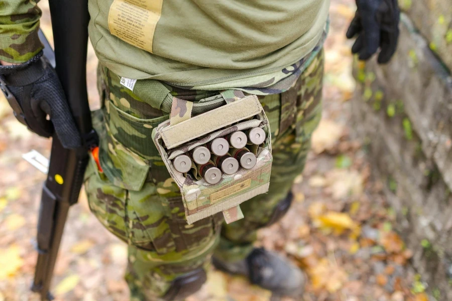 Person in Green Camouflage Print Pants Carrying Shotgun Shells