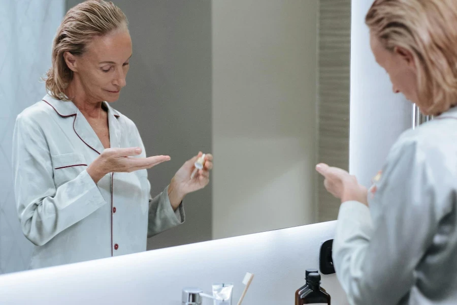 Woman Using Cosmetic Serum in Bathroom