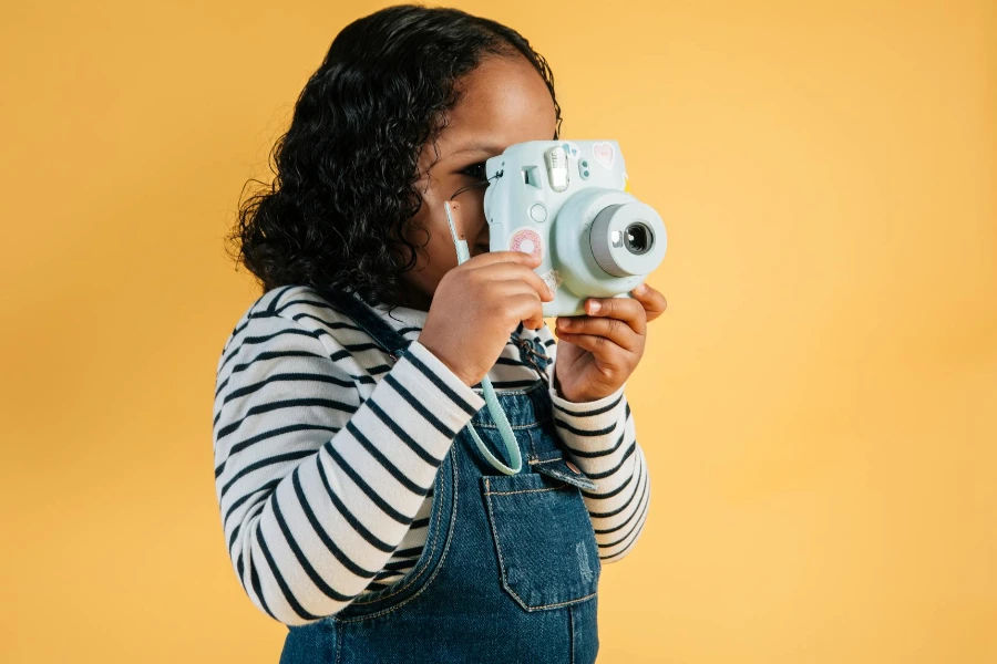 Focused little African American girl in casual wear taking pictures