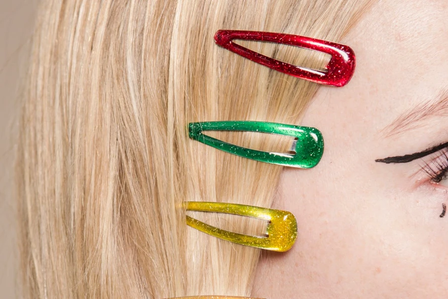 Crop anonymous female with red green and yellow hair clips on head on beige background