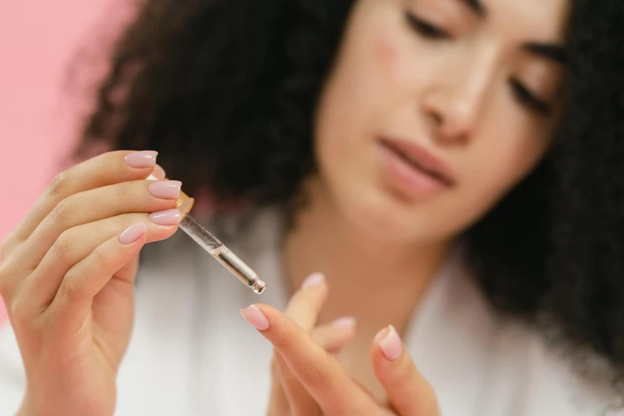 Close-up of Woman Putting Serum on Her Finger with the Use of a Pipette