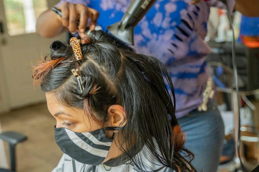 A Person Wearing Face Mask Having her Hair Blow Dry