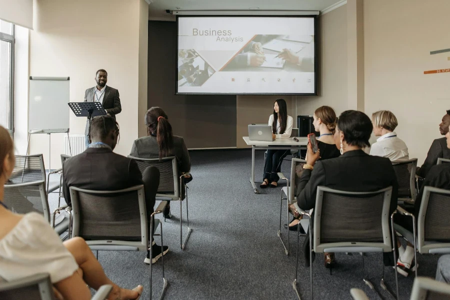 A Man Speaking in Front of the People Sitting Inside the Conference Room