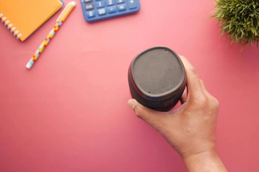 Hand Holding Portable Speaker on Desk