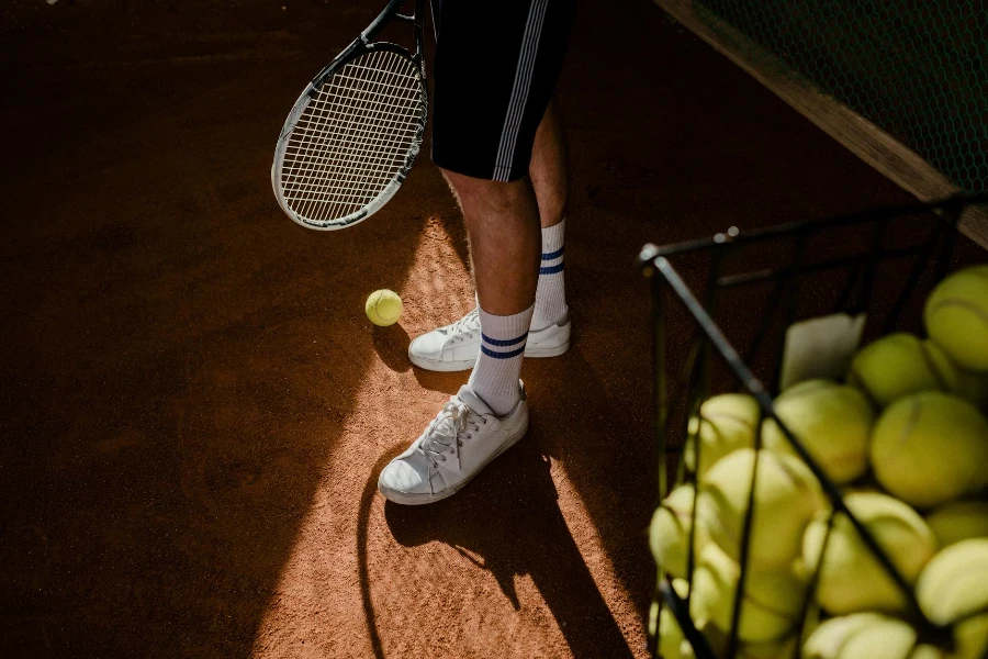 Person in White Sneakers and Black Shorts Standing on Tennis Court