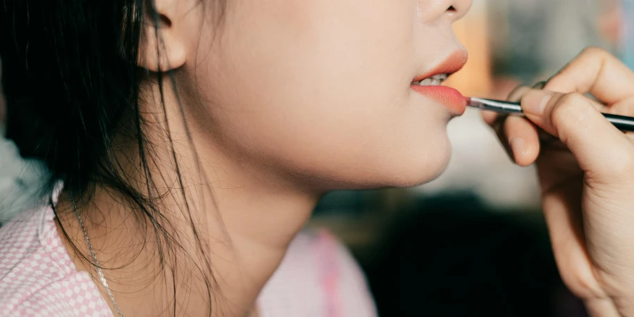 Close-up of Painting Woman Lips with Lipstick
