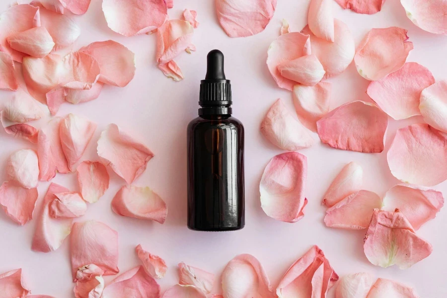 Set of pink petals and bottle on table