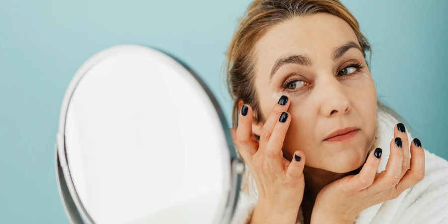 A Woman Looking at the Mirror while Applying a Cream on her eyes