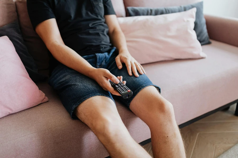 Person in Black T-shirt and Blue Denim Shorts Sitting on a Sofa