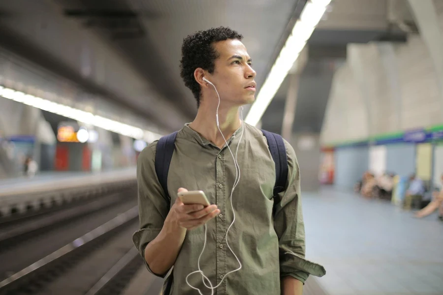 Young ethnic man in earbuds listening to music