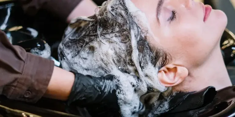 Lady washing her hair at a saloon with shampoo