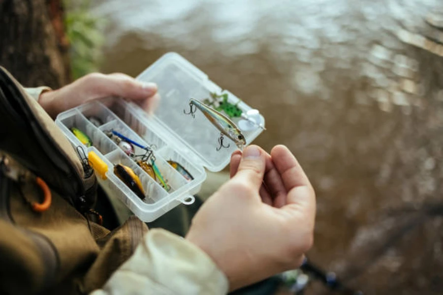 Man holding small tacklebox next to water