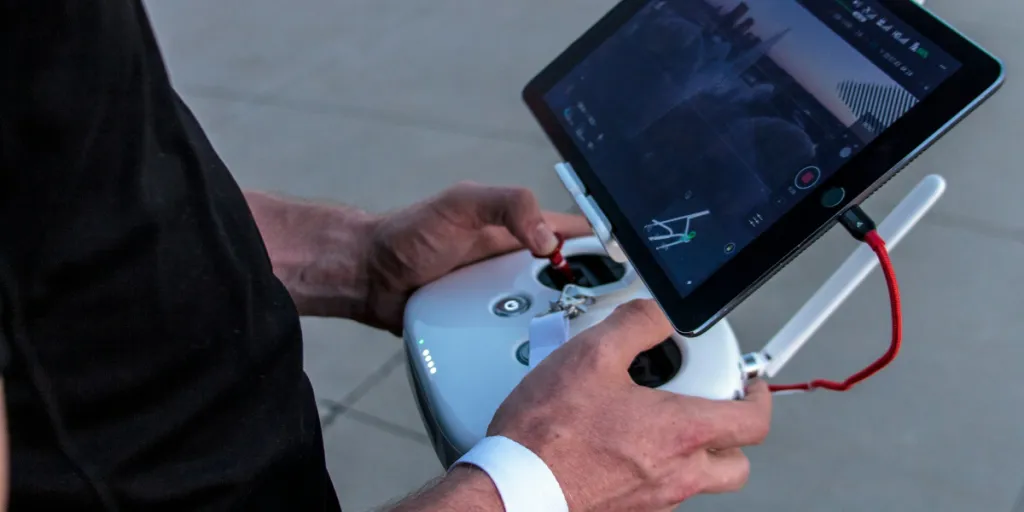 Person flying a drone with a controller and tablet