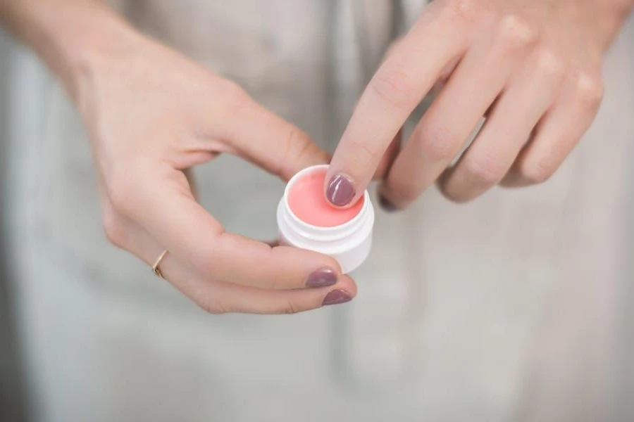 Person taking a scoop from lip balm