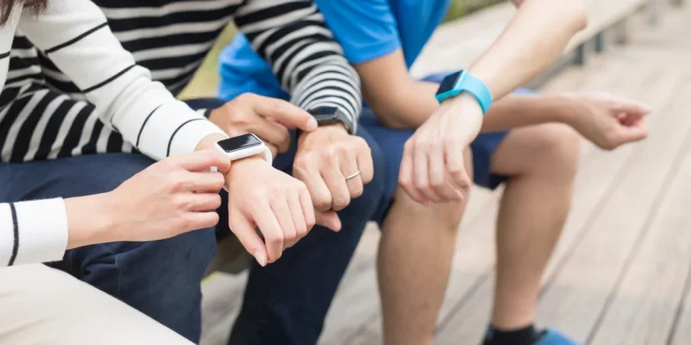 Three people outside all looking at their smartwatches