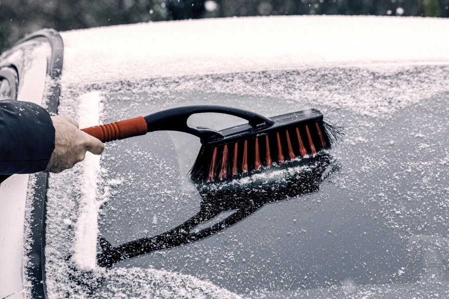 winter brush and scraper clearing car after snow blizzard