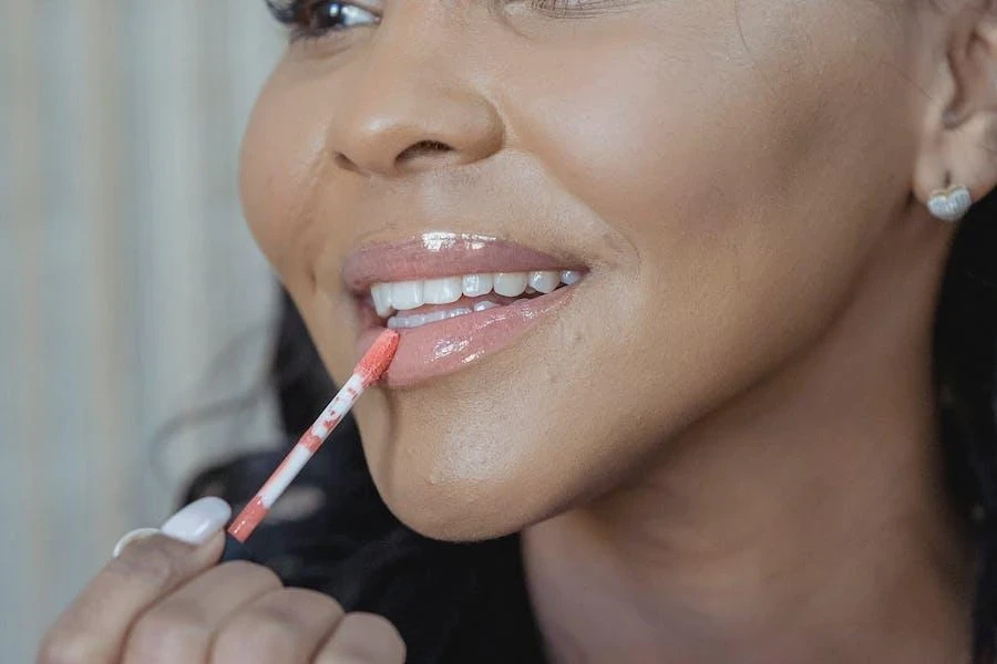 Woman applying lip gloss on her beautiful lips