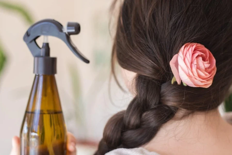 Woman holding hairspray next to her hair