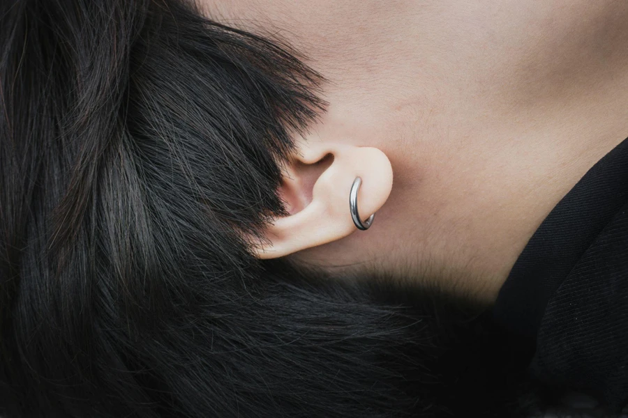 woman in short hair wearing silver huggie earrings.